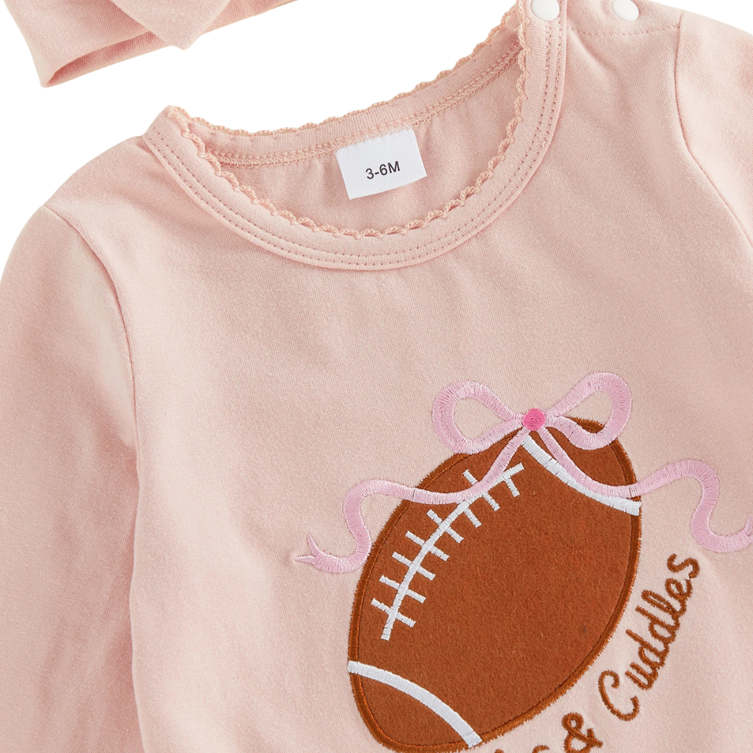 Close-up of the Huddles and Cuddles American football embroidery and lace neckline on a pink baby girl romper.