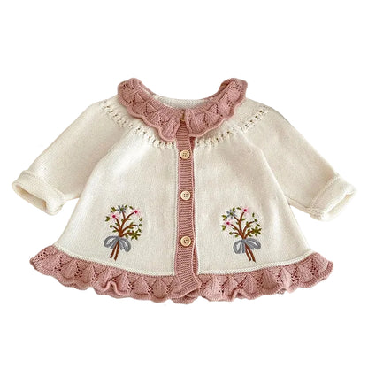 Ivory baby girl knit cardigan with pink scalloped ruffle trim and front floral embroidery.