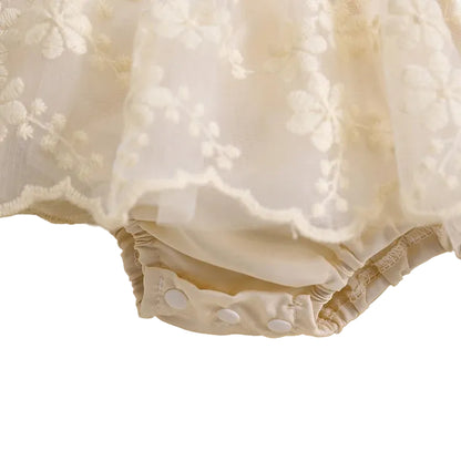 Close-up showing bottom snap closures on cream baby floral lace romper dress for easy diaper changes