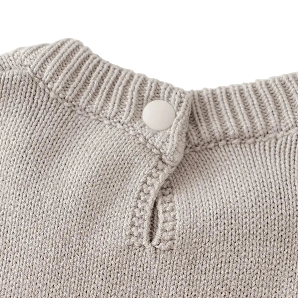 Close-up of the fastened button closure on the back neckline of the light gray knit dress.