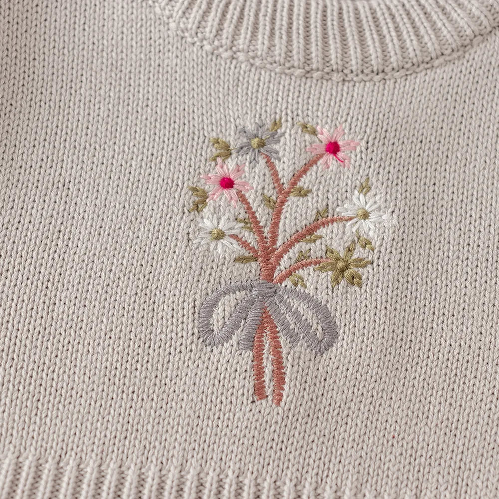 Close-up of the vintage-inspired floral bouquet embroidery on the chest of the light gray knit dress.