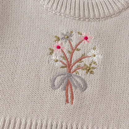 Close-up of the vintage-inspired floral bouquet embroidery on the chest of the light gray knit dress.