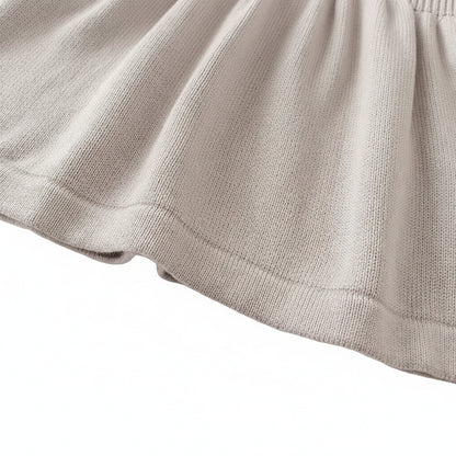 Close-up of the bottom hemline of the light gray baby girl knit sweater dress.