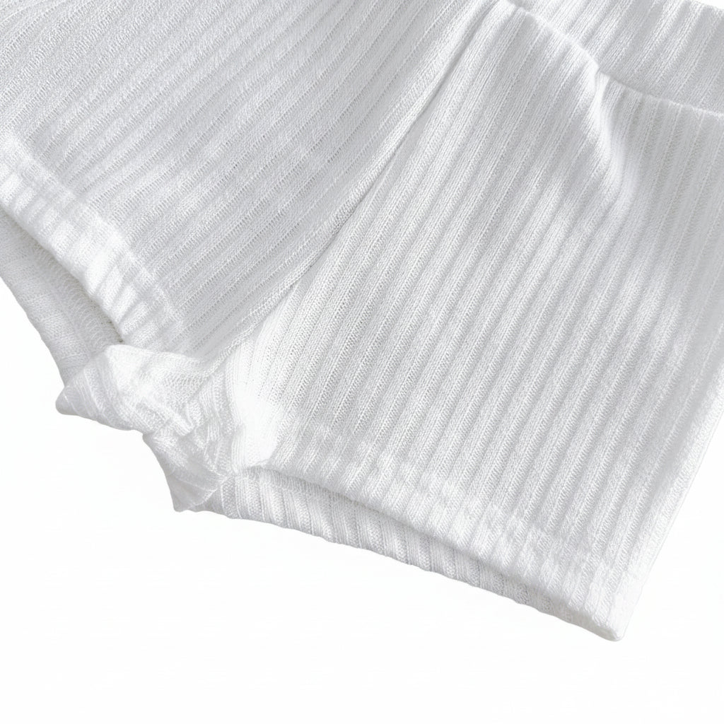 Close-up studio shot showing the stitched leg opening hem on the marshmallow white ribbed knit toddler shorts.