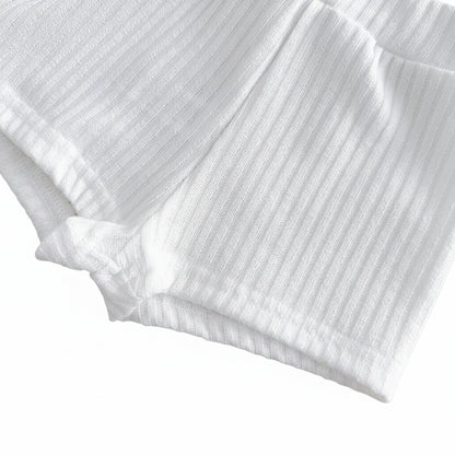 Close-up studio shot showing the stitched leg opening hem on the marshmallow white ribbed knit toddler shorts.
