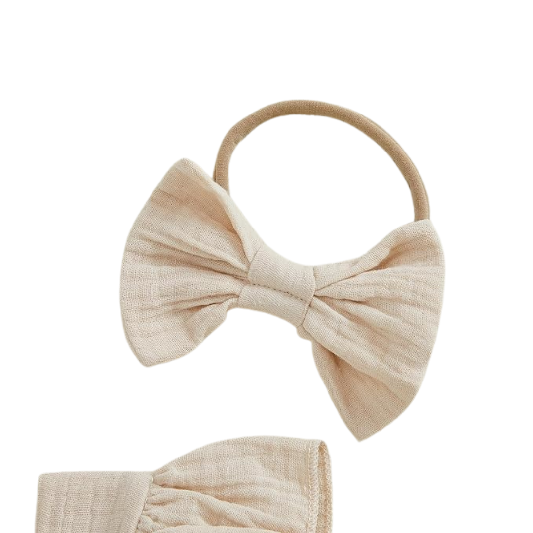 Close up of cream matching oversized bow headband for baby girl 1st birthday outfit set