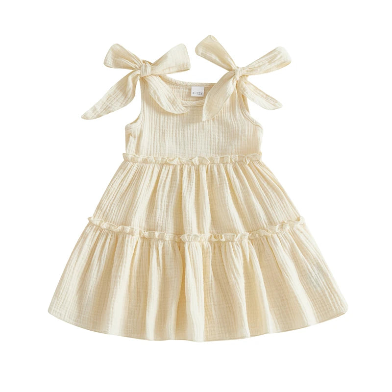 Soft Vanilla Cream textured cotton sun dress for toddlers featuring a three-tier ruffle skirt and shoulder ties.