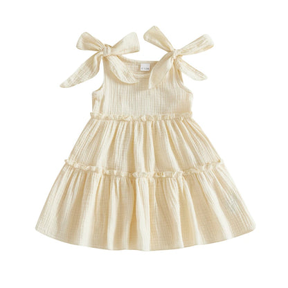 Soft Vanilla Cream textured cotton sun dress for toddlers featuring a three-tier ruffle skirt and shoulder ties.