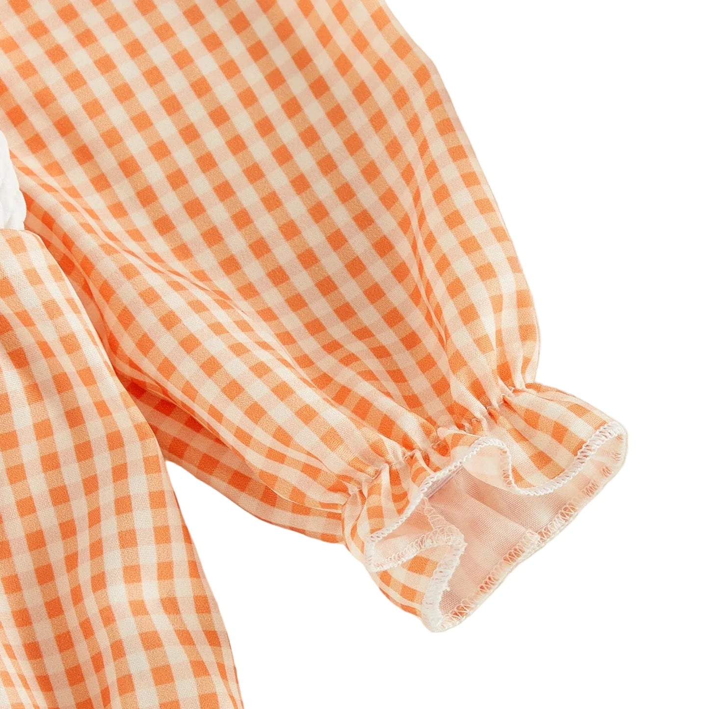 Close-up detail of the long sleeve on the baby girl orange gingham romper, showing the elastic ruffled cuff.