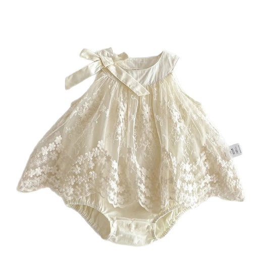 Flat lay of a baby girl sleeveless princess romper dress in Pearl Ivory featuring intricate floral lace embroidery, a decorative shoulder bow, and a built-in cotton bodysuit on a clean white background.