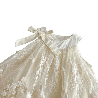 Top-down angled shot focusing on the neckline, collar stitch detail, and shoulder bow tie of the Pearl Ivory infant romper dress.