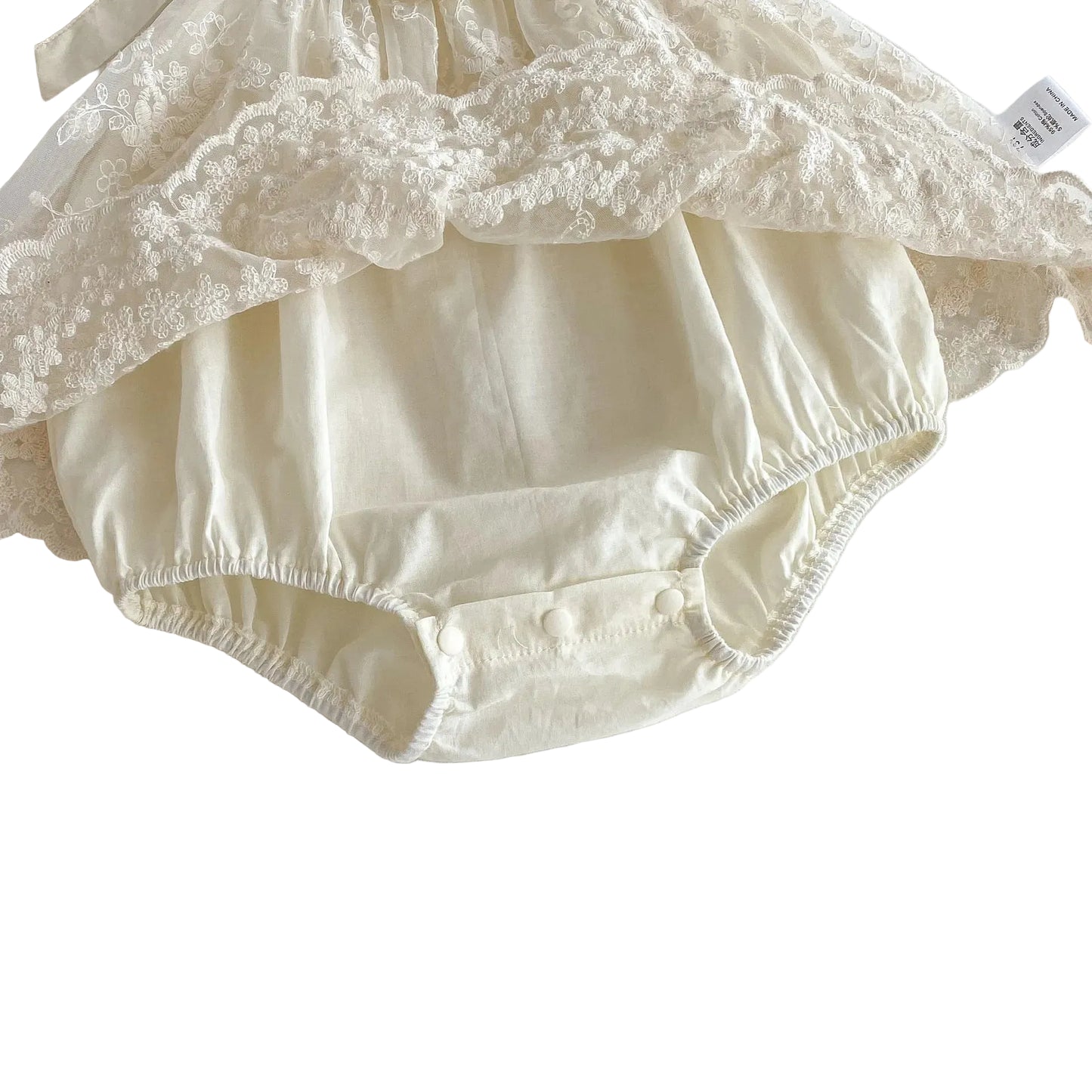 Detailed close-up showing the soft, breathable cream cotton bodysuit base underneath the sheer embroidered lace overlay of the infant dress.