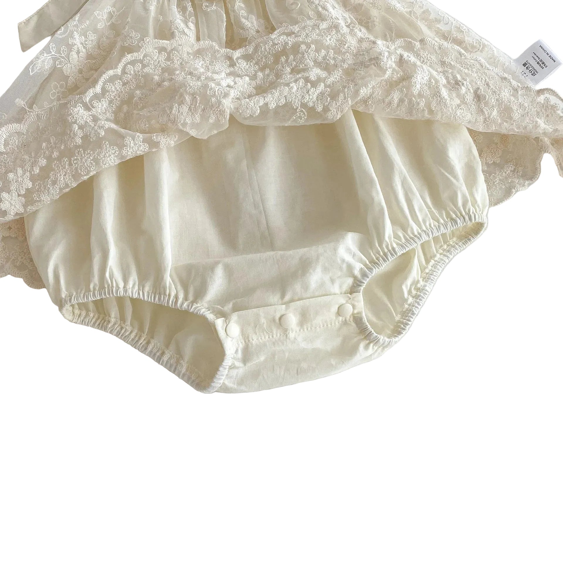 Detailed close-up showing the soft, breathable cream cotton bodysuit base underneath the sheer embroidered lace overlay of the infant dress.