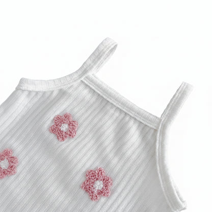 Close-up view of the clean scoop neck border and sleeveless shoulder straps on the petal white ribbed knit toddler top with pink flower accents.