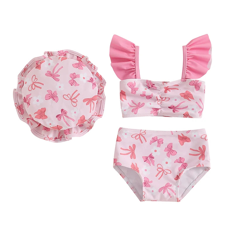Three-piece baby girl swimsuit set featuring a soft pink bow print ruffle tankini, swim shorts, and matching sun hat.