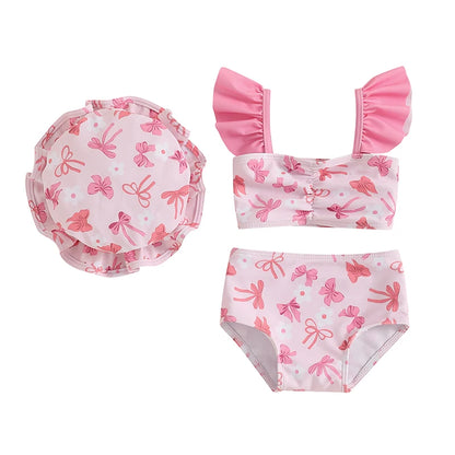Three-piece baby girl swimsuit set featuring a soft pink bow print ruffle tankini, swim shorts, and matching sun hat.