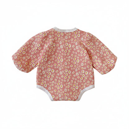 Back view of the baby girl pink daisy floral long sleeve bubble romper laid flat on a white background.