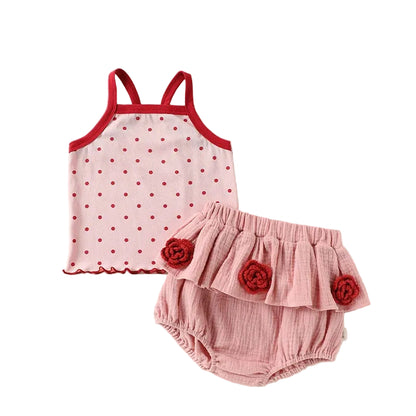 Two-piece baby girl summer clothing set featuring a pink sleeveless top with red polka dots and matching pink tiered ruffle bloomers with red fabric rosette flowers.