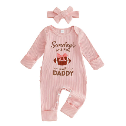 Front view of baby girl pink ribbed long sleeve football romper with "Sundays With Daddy" graphic and matching bow headband on a white background.