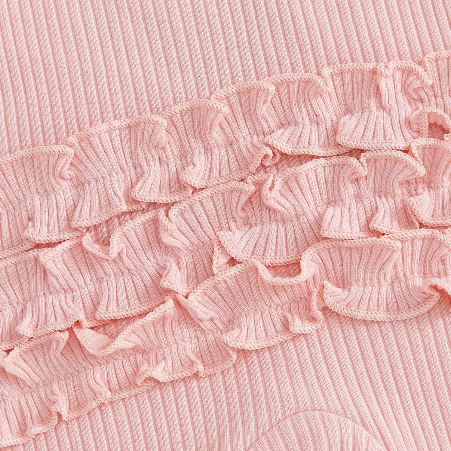 Close-up detail of the pink ribbed cotton blend fabric and tiered ruffles on the back of the baby girl romper.