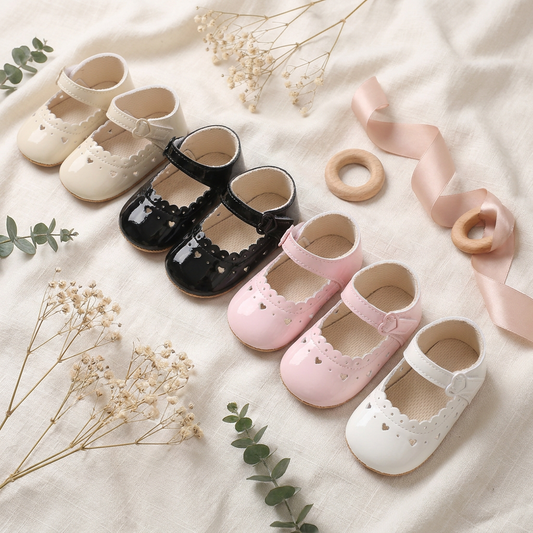 Flat lay display of baby girl Mary Jane dress shoes in beige, black, pink, and white.