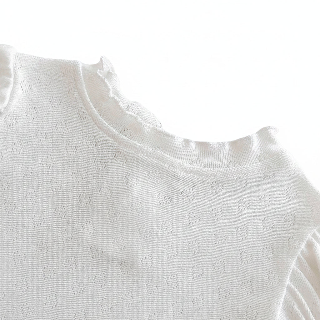 Close-up of the stretch pullover O-neck collar with ruffled scalloped detailing on the white baby bodysuit shirt.