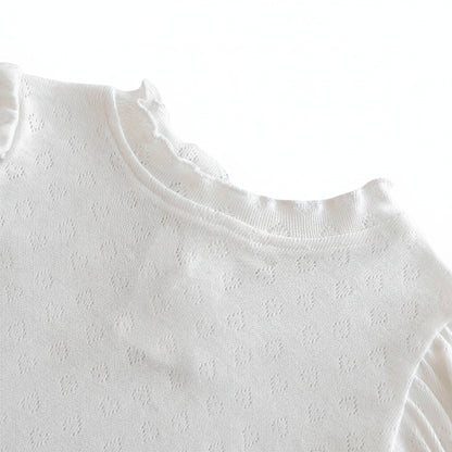 Close-up of the stretch pullover O-neck collar with ruffled scalloped detailing on the white baby bodysuit shirt.