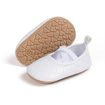 Angle view of a pair of Kidsely white quilted baby girl Mary Janes, displaying the soft rubber traction sole.