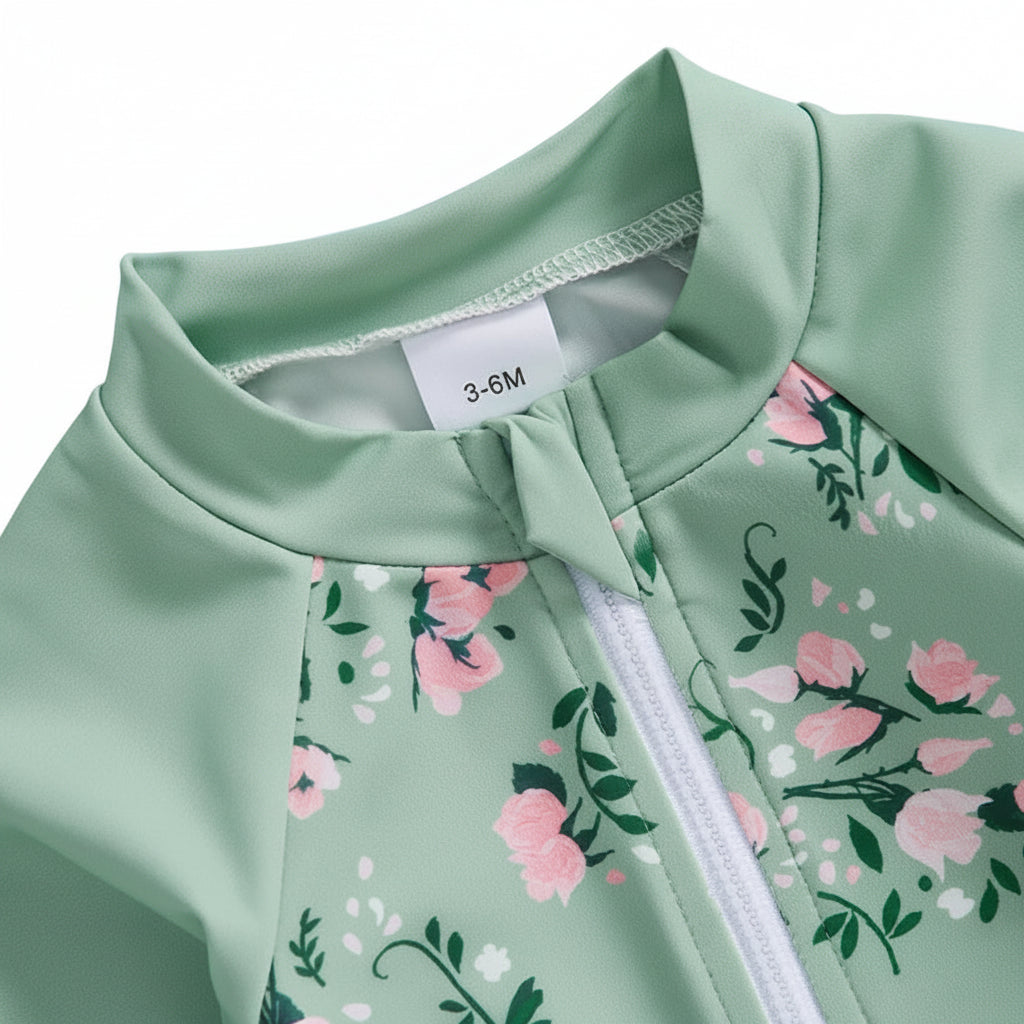 Close-up detail of the front half-zipper on the sage green baby swimsuit featuring a protective fabric chin guard to prevent skin irritation.