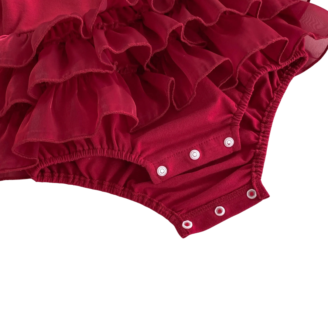 Close-up showing the convenient bottom snap closures on the baby girl deep red ruffle romper dress designed for easy diaper changes.