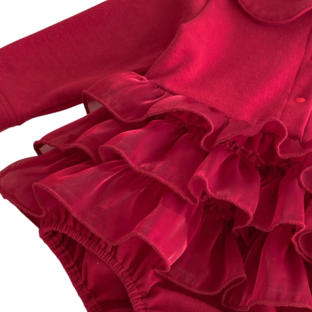 Close-up side profile of the voluminous layered tulle ruffle skirt on the baby girl deep red romper dress.