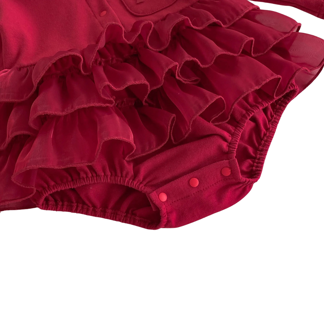Detailed angled shot of the deep red romper dress showing the lower diaper snaps beneath the layered tulle ruffle skirt.