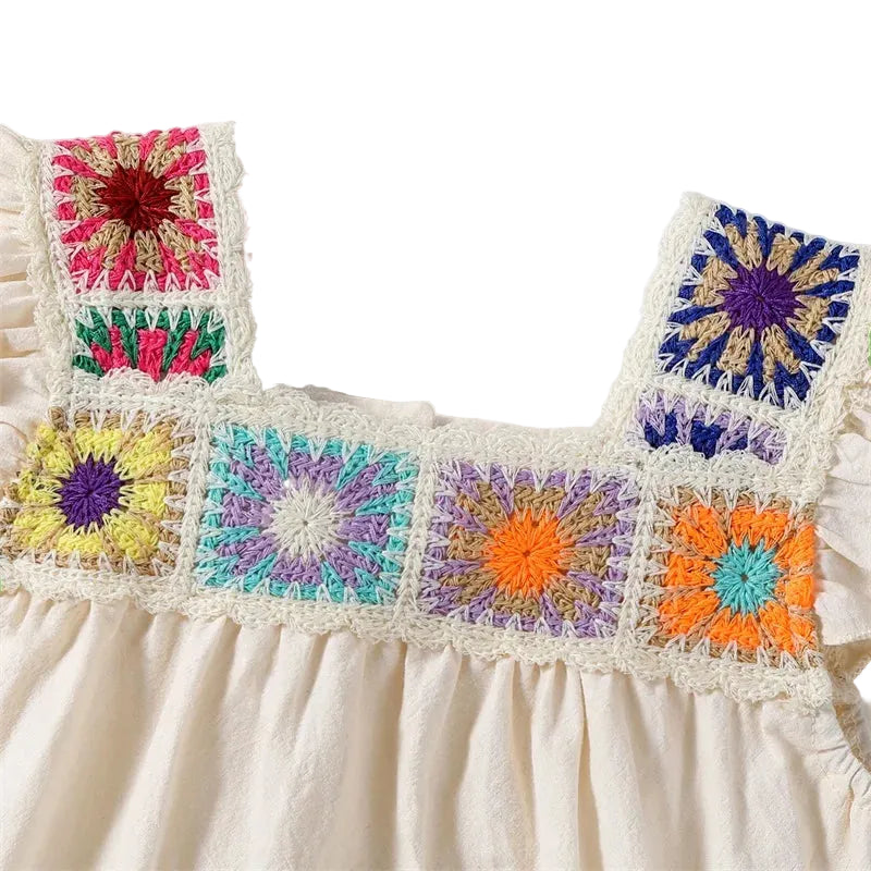 Detailed close-up view of the square neckline and colorful hand-knit crochet floral patches on the beige infant bodysuit.
