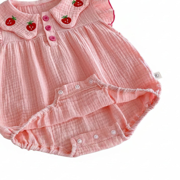 Detailed view of the bottom crotch area of the pink muslin infant bodysuit showing the open snap buttons designed for easy diaper changes.