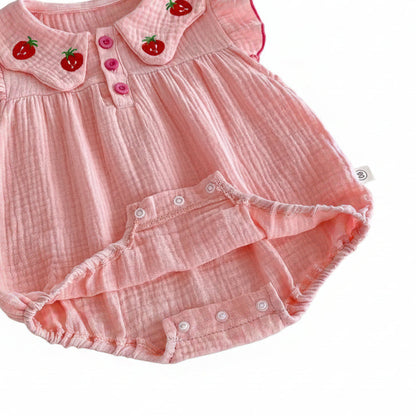 Detailed view of the bottom crotch area of the pink muslin infant bodysuit showing the open snap buttons designed for easy diaper changes.