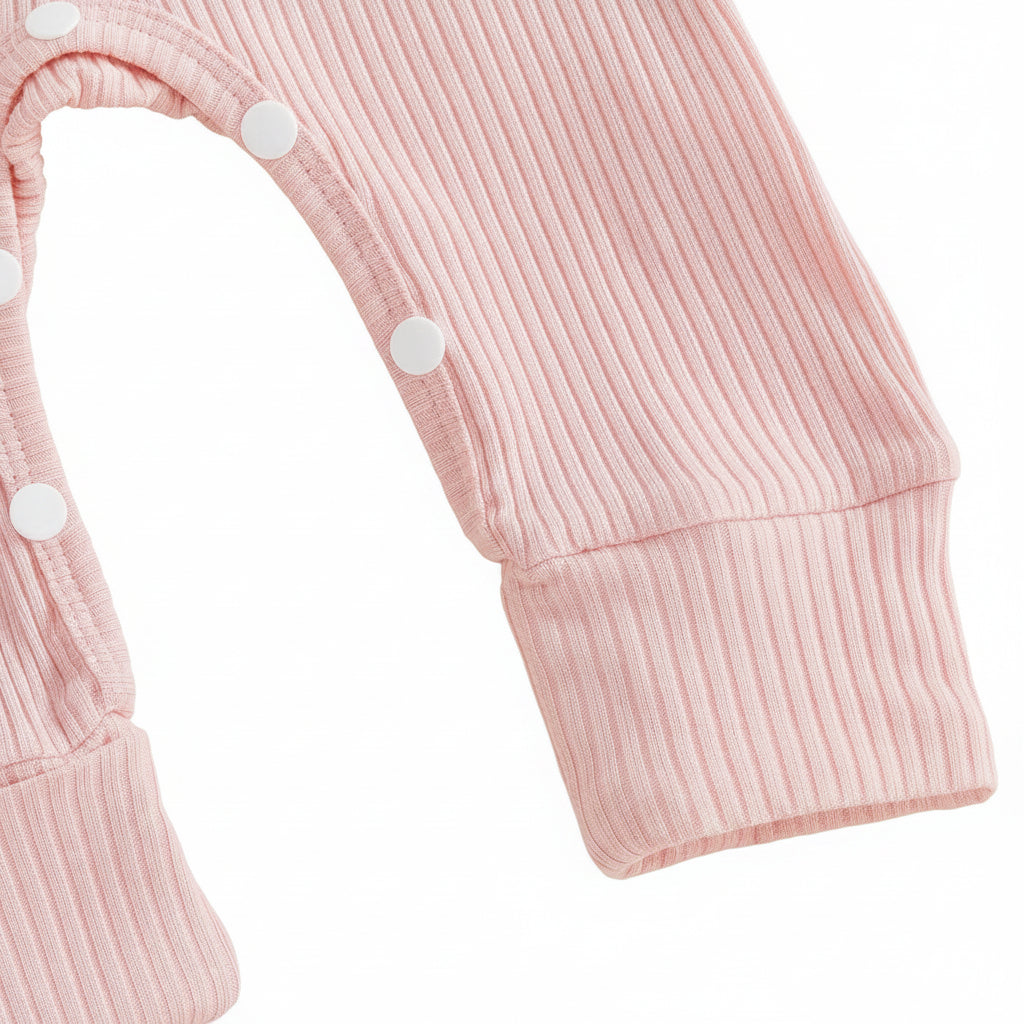 Close-up of the convenient bottom snap closures on the leg of the pink ribbed baby romper.