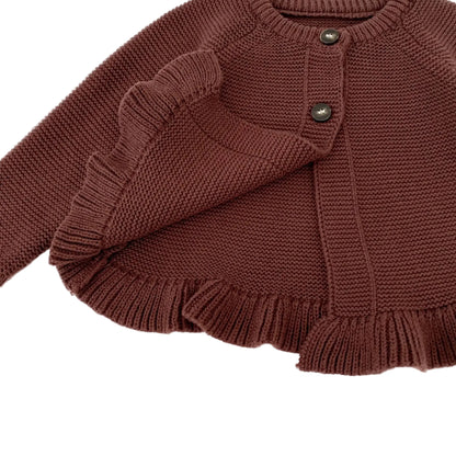 Close-up detail showing the ribbed ruffled hemline, thick knit texture, and two-button front closure of the baby girl brown cardigan.