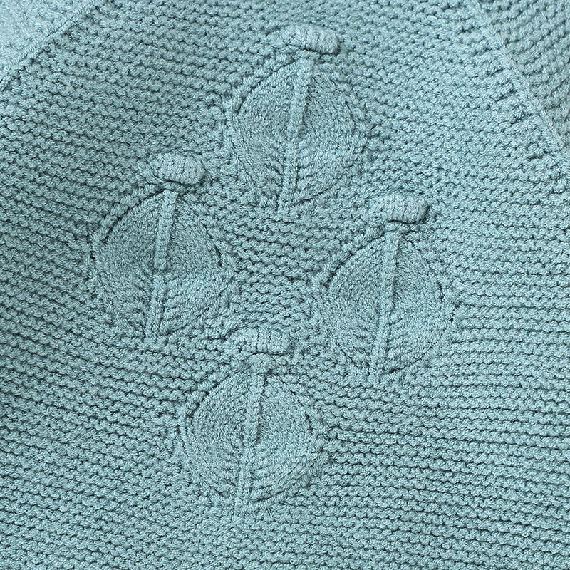 Detailed close-up of the vintage-inspired raised diamond lattice textured knit pattern on the chest of the teal baby romper.