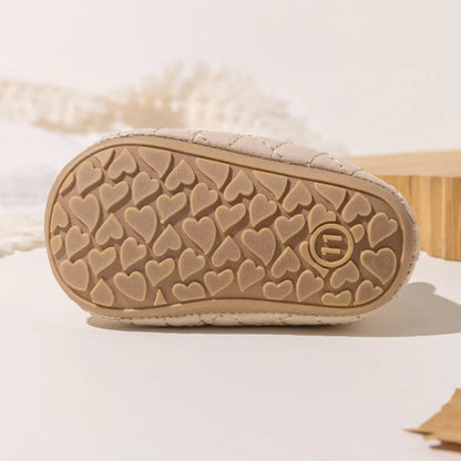 Close-up view of the textured heart pattern on the bottom of a Kidsely beige baby girl pre-walker shoe sole.