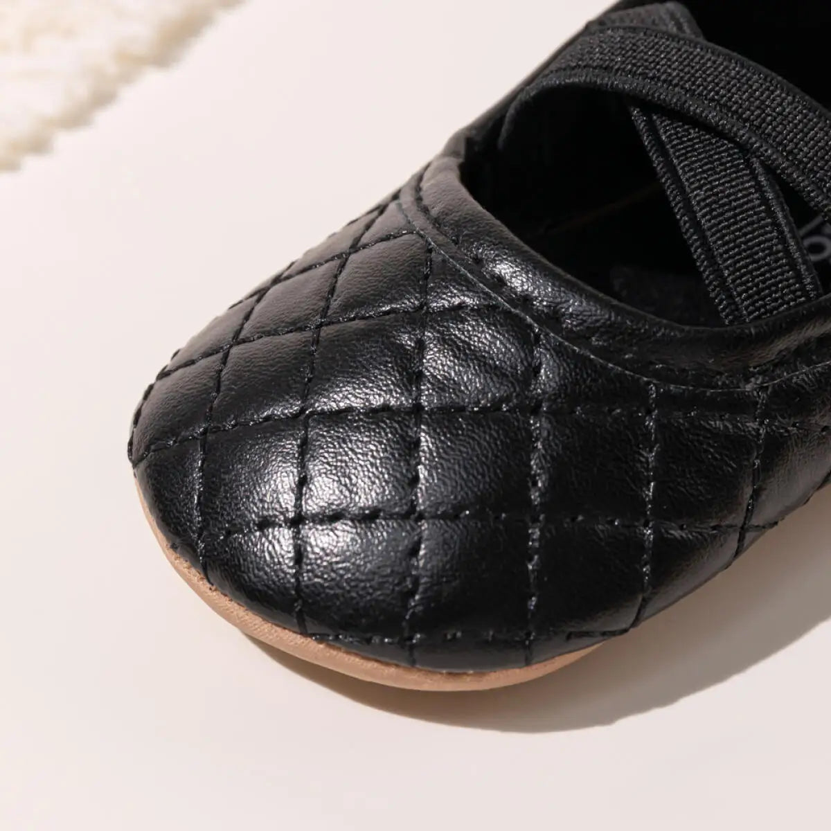 Macro close-up detailing the elegant checkerboard quilted stitching on the toe of a Kidsely black baby girl shoe.
