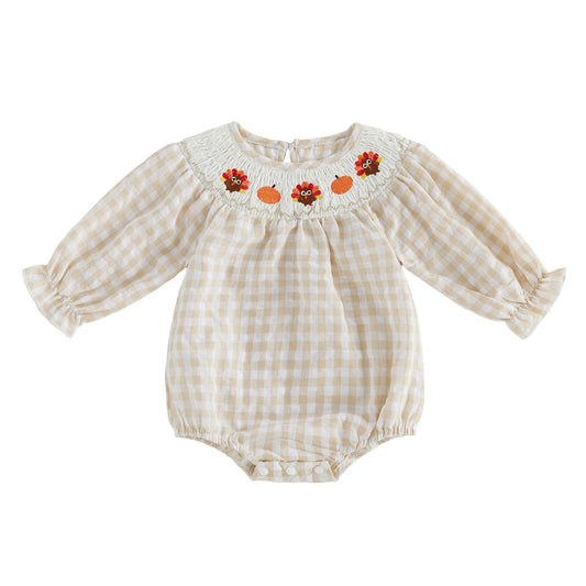 Front view of the baby girls beige gingham smocked Thanksgiving romper with turkey and pumpkin embroidery.