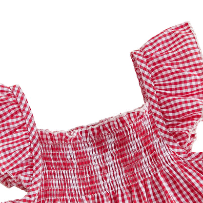 Close-up texture shot highlighting the stretchy elastic shirred smocked bodice and ruffled flutter flying sleeve straps on the red gingham baby top.