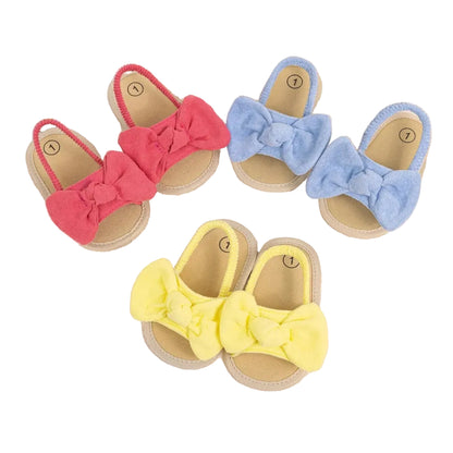 Three pairs of baby girl soft sole sandals with plush bows in pink, blue, and yellow colors.