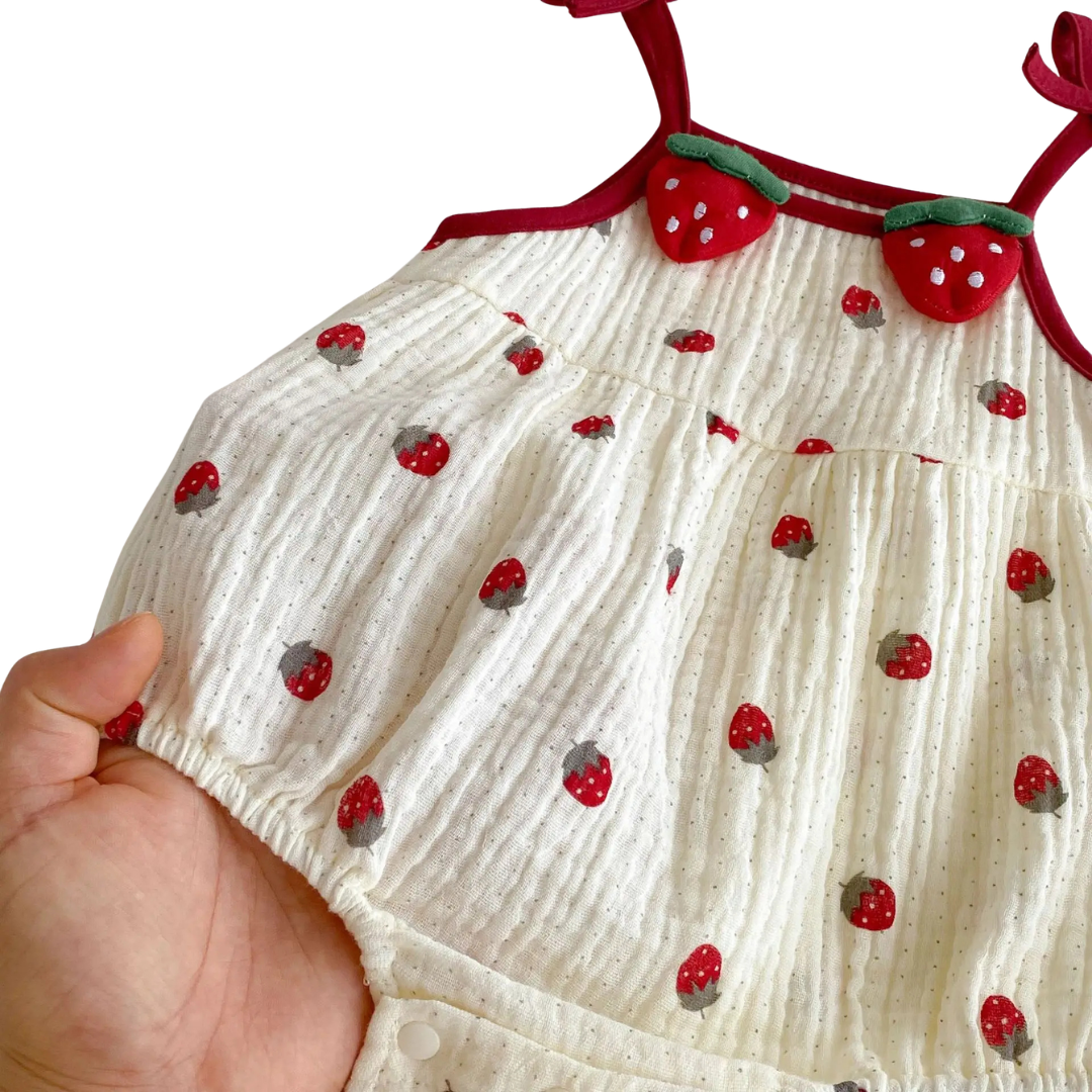 A close-up view of the lightweight, crinkle-textured cotton blend fabric on the cream strawberry baby sunsuit.