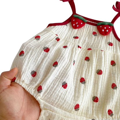 A close-up view of the lightweight, crinkle-textured cotton blend fabric on the cream strawberry baby sunsuit.