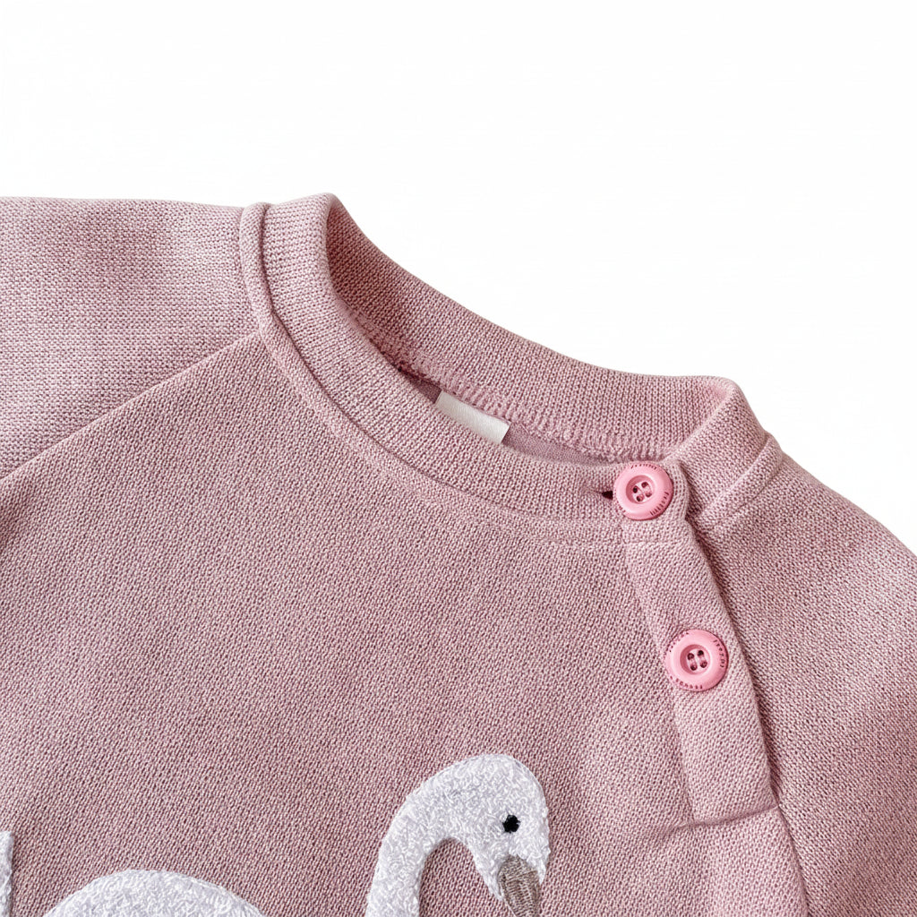 Close-up detail of the crewneck collar and practical two-button shoulder closure on the blush pink baby girl sweatshirt.