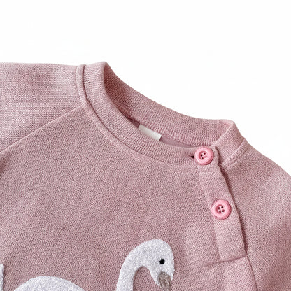 Close-up detail of the crewneck collar and practical two-button shoulder closure on the blush pink baby girl sweatshirt.