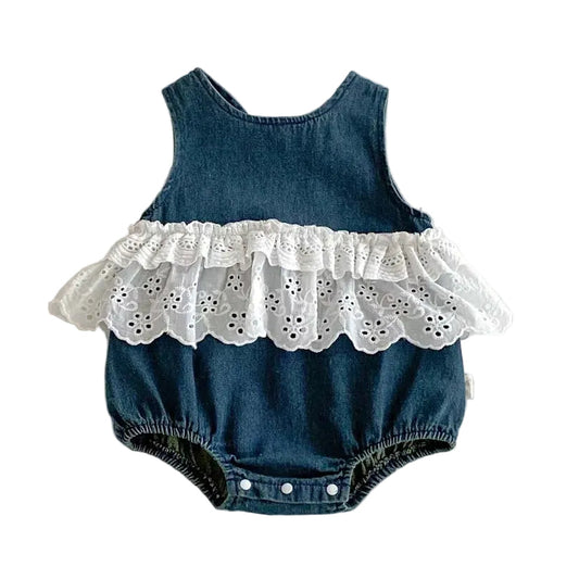 Flat lay of an infant baby girl’s dark wash denim bubble romper featuring white eyelet lace ruffles and a sleeveless design on a clean white background.