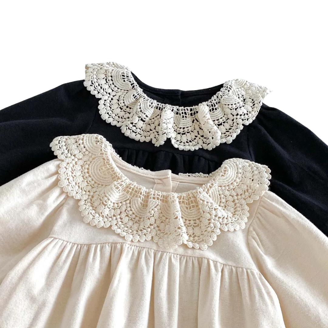 Close-up of intricate white embroidered lace collar on black and cream long sleeve baby rompers