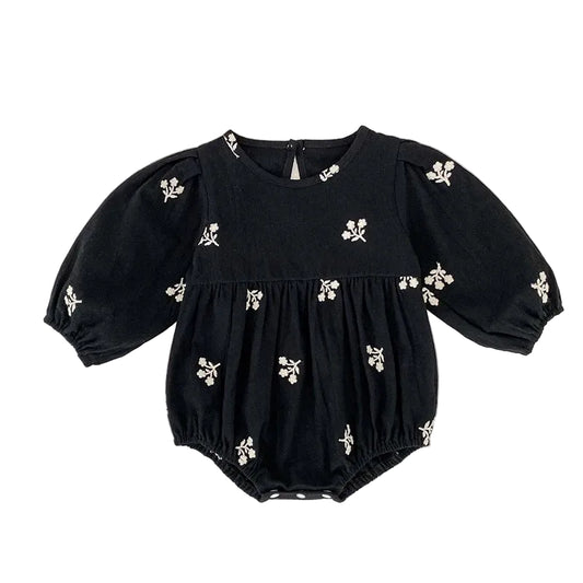 Front view of a baby girls black bubble romper featuring white floral embroidery and long puff sleeves.